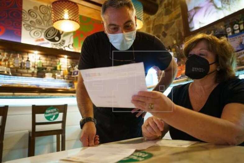 Imagen de archivo de un camarero comprobando el certificado covid de una clienta / EFE Ramón de la Rocha